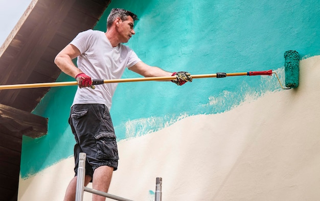 worker paints facade walls house with paint using paint roller 1086986 243